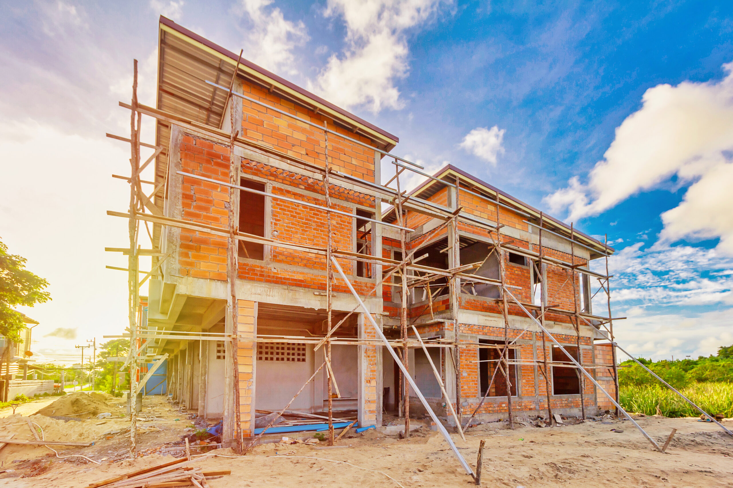 Unfinished two-story brick house structure with scaffolding against a blue sky